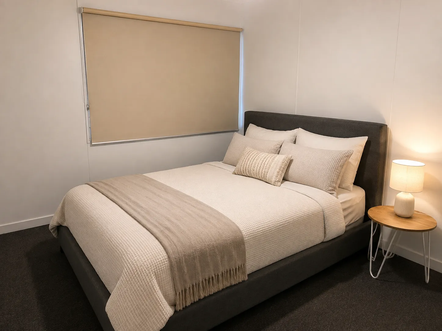 Second queen bedroom at Cozy on Hudson in Port Lincoln with upholstered charcoal bedhead, layered neutral bedding and bedside lamp