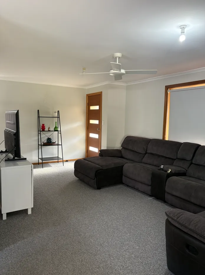 Open plan lounge room at Cozy on Pearson with a large grey sectional sofa and smart TV, Port Lincoln pet friendly holiday house
