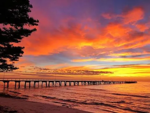 Tumby Bay jetty silhouetted against a vivid orange sunset over the water
