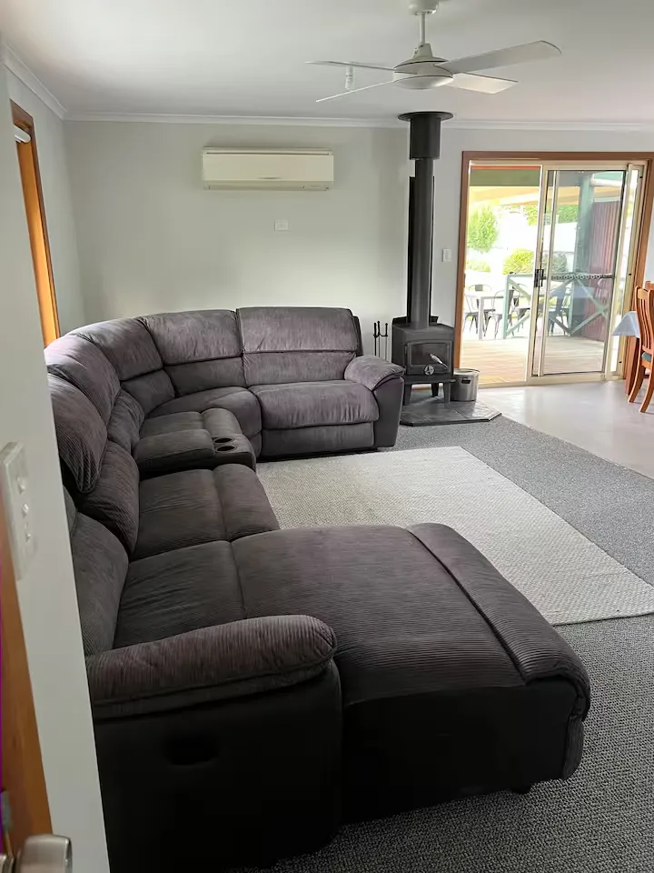 Living room at Cozy on Pearson with a wood fire, corner recliner lounge and sliding doors to the deck